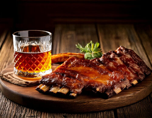 Rocks glass of bourbon next to a bbq rack of ribs